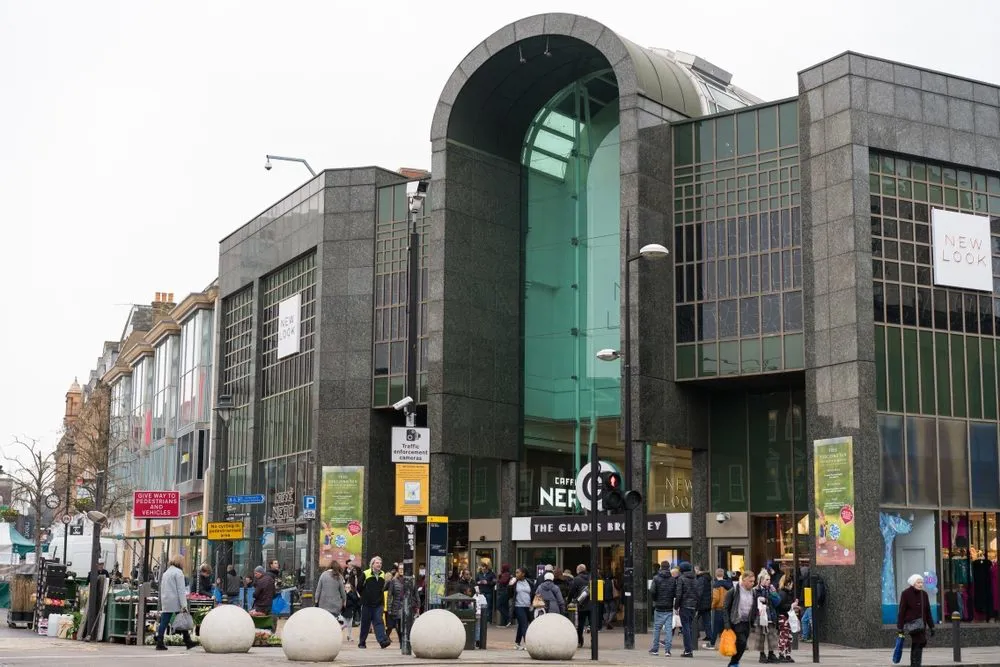 A photo of a large building made of dark stone and glass on a street corner