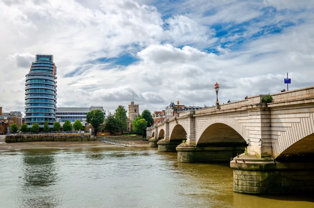 A photo of a bridge over a river with buildings in the background