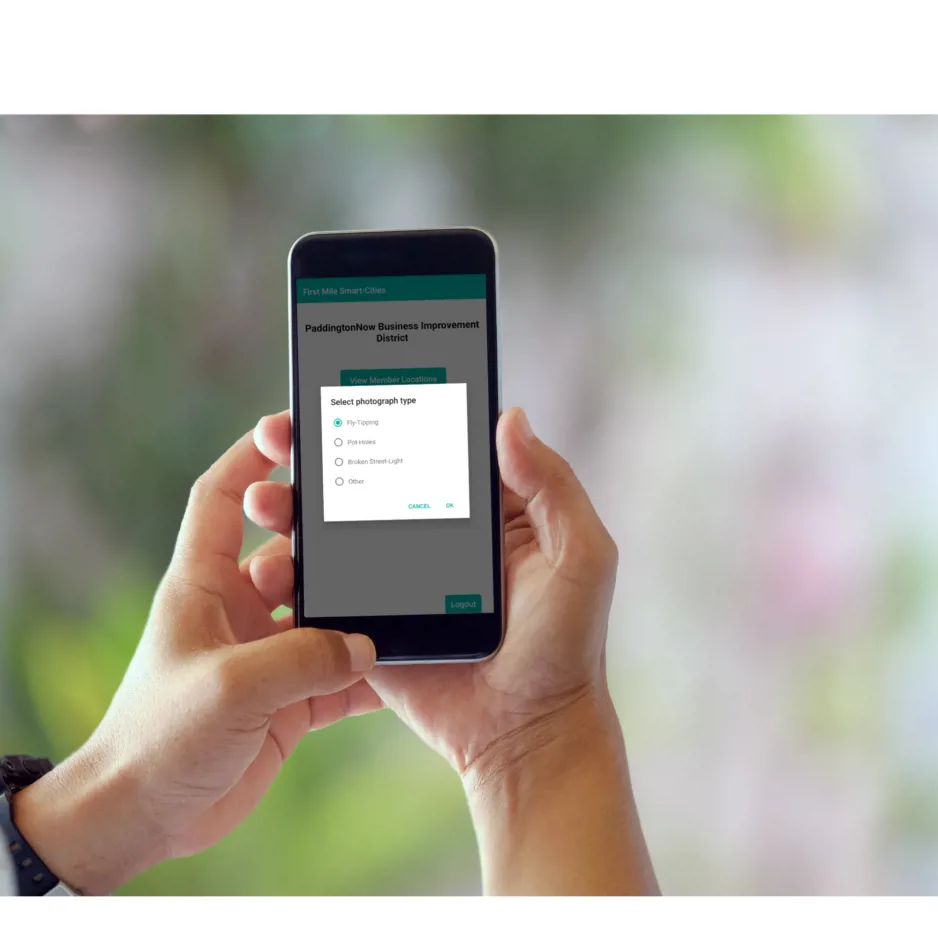 Close of photo of hands holding a mobile phone using the First Mile Smart Cities app
